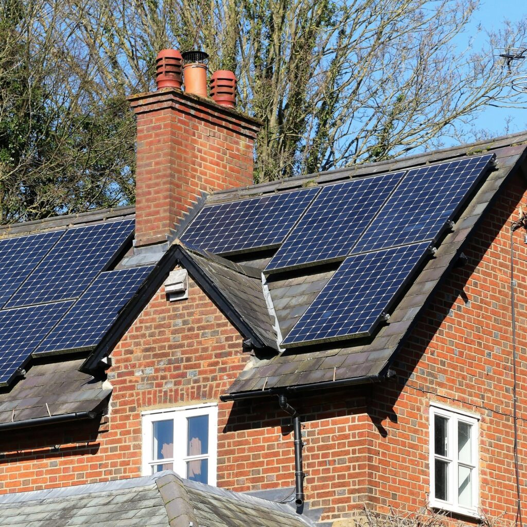 A red brick house with a chimney and blue solar panels attached to the top