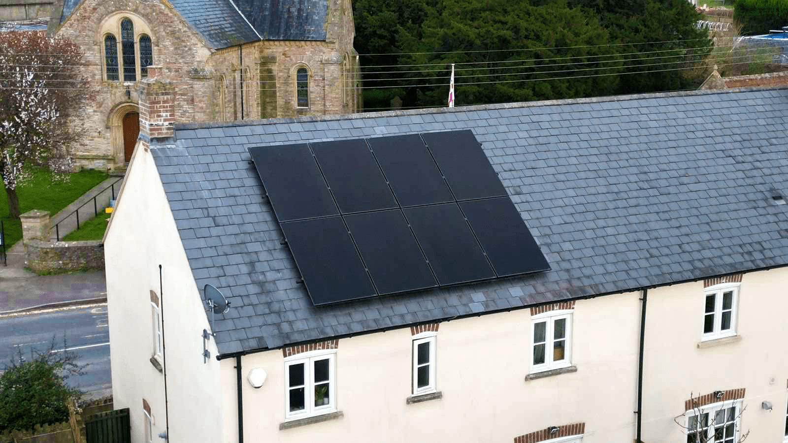 A solar panel unit on top of a white house with grey/blue tiled roofing